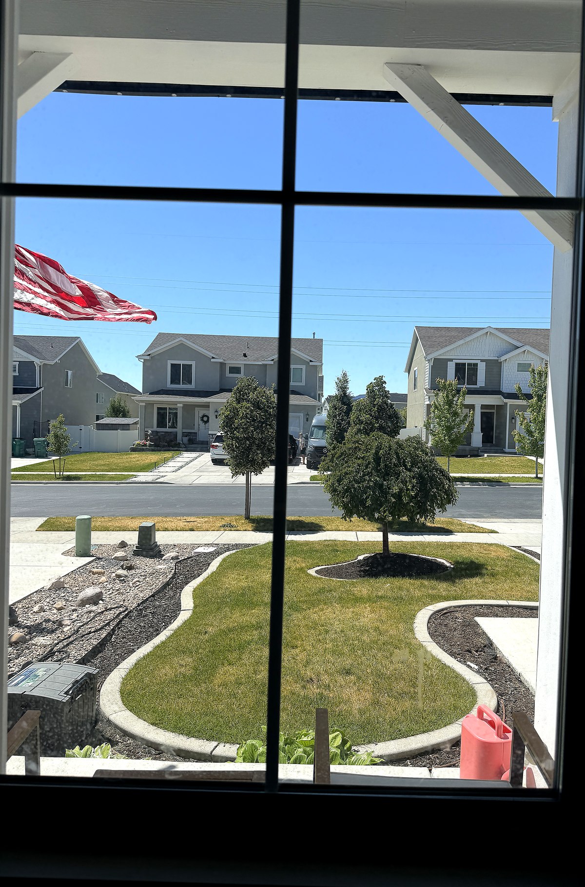 Crystal clear view through a freshly cleaned window — sunny neighborhood, lush green yard, blue sky